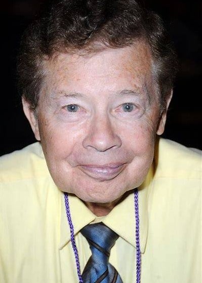 Lou Wagner was captured in the smiley face and looking at the front side wearing yellow shirt and grey and black tie